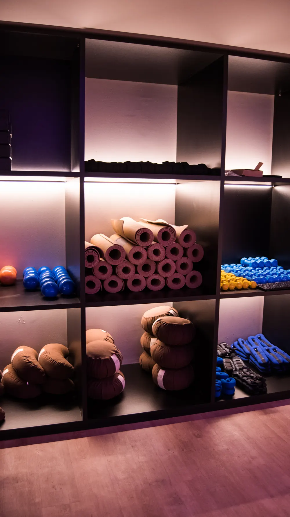 Estantería del estudio con esterillas, cojines y pequeñas pesas